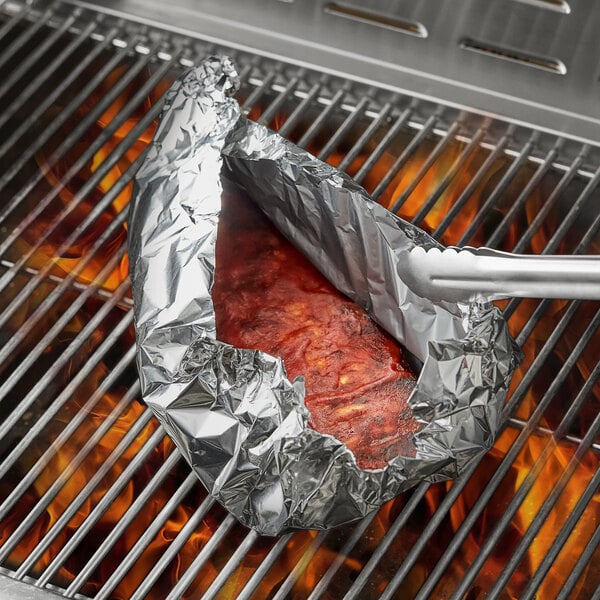 A piece of meat in Choice non-stick aluminum foil on a grill.