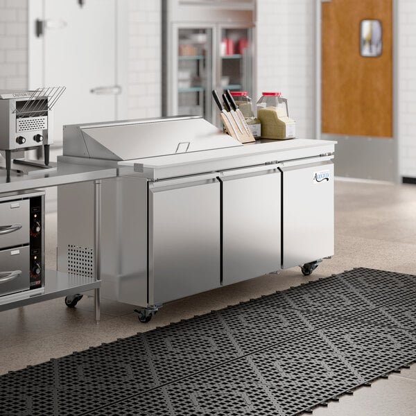 An Avantco stainless steel sandwich prep table on a large counter in a commercial kitchen.