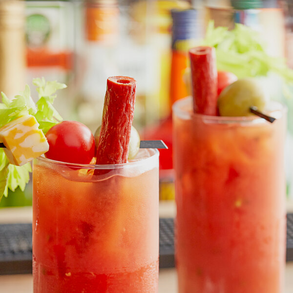 Two Bloody Mary drinks garnished with vegetables and a Benny's Original Meat Straw.