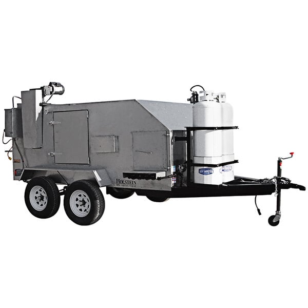 A large grey Holstein Manufacturing chicken and rib cooker on a trailer with a white tank.