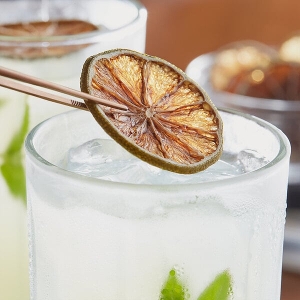 A glass of lemonade with a dried lime slice on the rim.