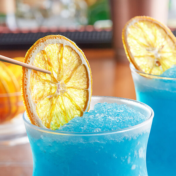 Two blue drinks garnished with dried navel orange slices.