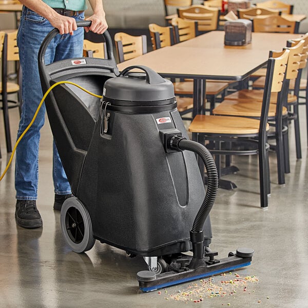 A person using a Viper Shovelnose wet/dry vacuum to clean a floor in a restaurant.
