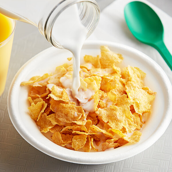 A bowl of Kellogg's Corn Flakes cereal with milk being poured into it.