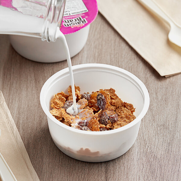 A bowl of Kellogg's Raisin Bran cereal with milk being poured into it.