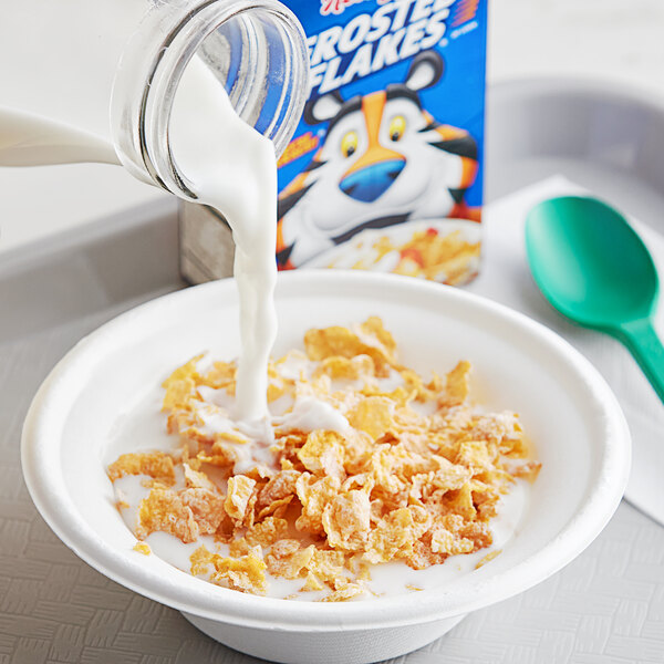 A bowl of Kellogg's Frosted Flakes cereal with milk being poured into it.