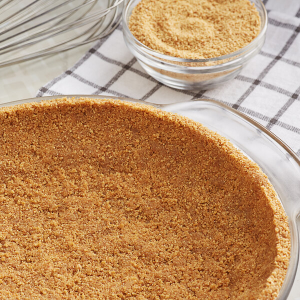 A glass pie dish with a pie crust filled with brown powder made with Kellogg's Graham Cracker Crumbs.