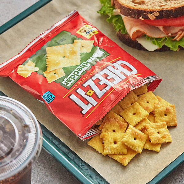 A tray with a sandwich and a bag of Cheez-It White Cheddar Crackers.