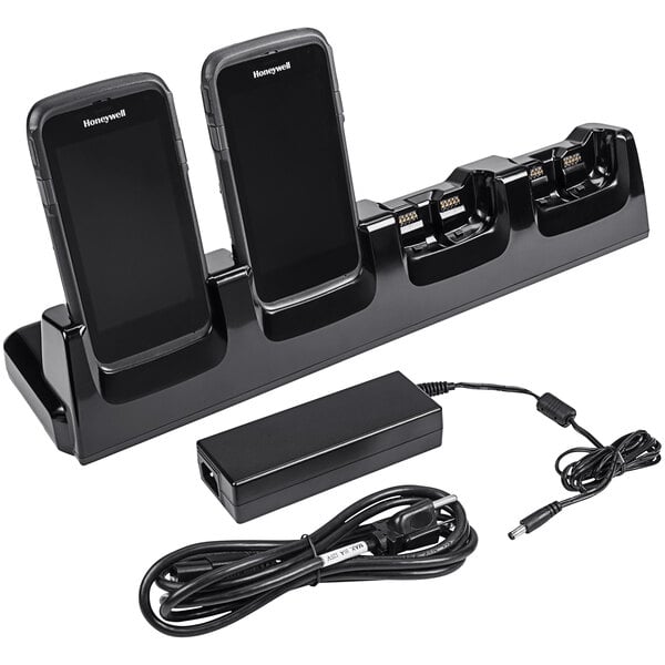 A black Honeywell 4-slot charge dock with CT50 and CT60 mobile computers and cables on a counter.