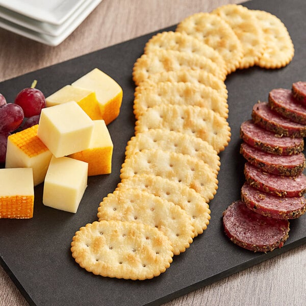 A plate of cheese and Kellogg's Town House crackers with grapes on a table in a deli.