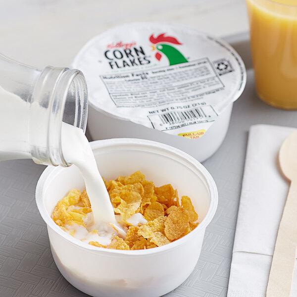 A bowl of Kellogg's Corn Flakes cereal with milk being poured into it.