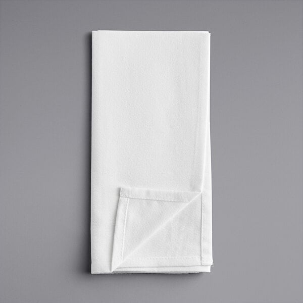 A folded white Oxford Momie cloth napkin on a gray surface.