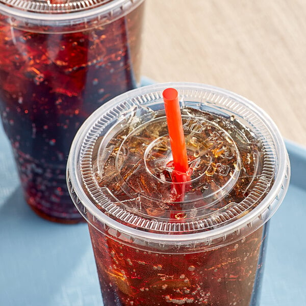 Two plastic cups with clear plastic flat lids and straws on a table.