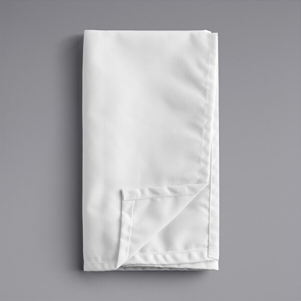 A folded white cloth napkin on a gray surface.