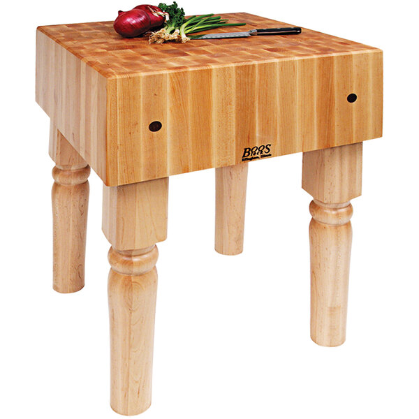 A John Boos maple butcher block table with green onions on it.