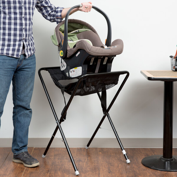 A man holding a Koala Kare black infant seat on a stand.