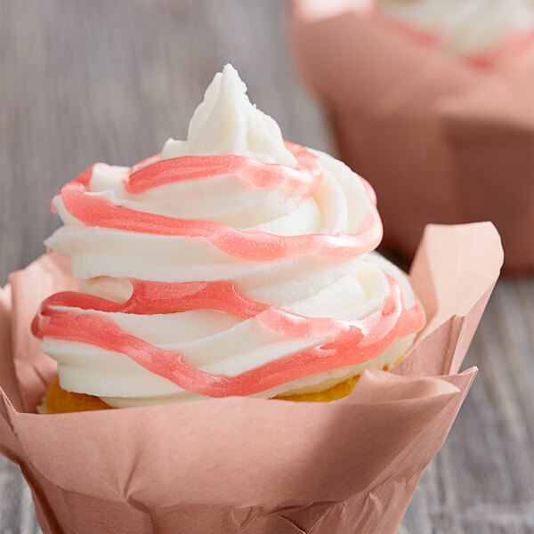 A close up of a cupcake with pink swirls of Satin Ice Pink Vanilla Glitter Glaze.