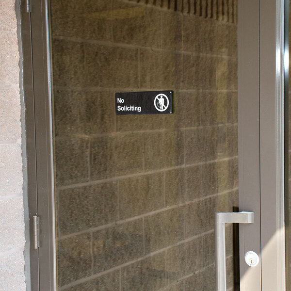 A glass door with a black and white Thunder Group no soliciting sign.