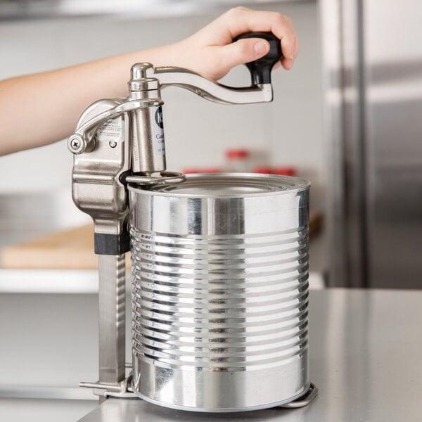 A person using a Nemco CanPRO manual can opener on a counter.