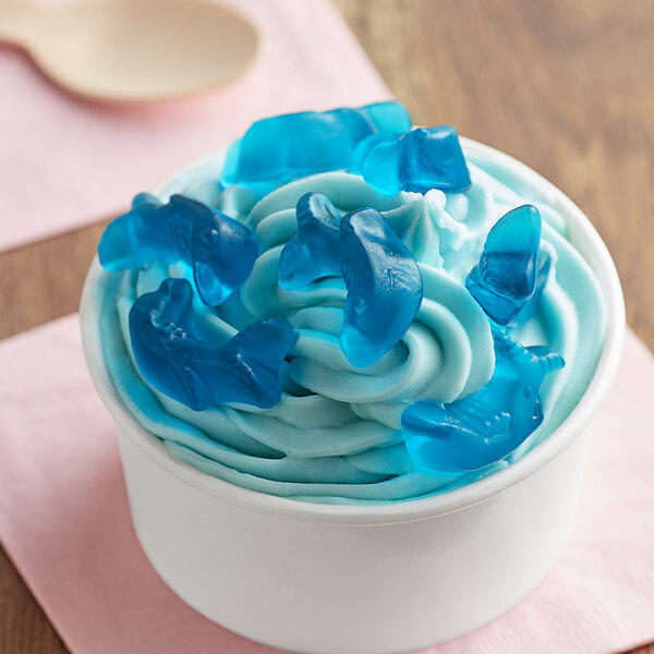 A cup of ice cream with blue gummy dolphins on top.