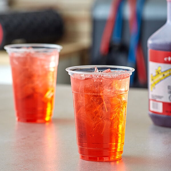 Two plastic cups with red Sqwincher cherry electrolyte beverage sitting on a table.