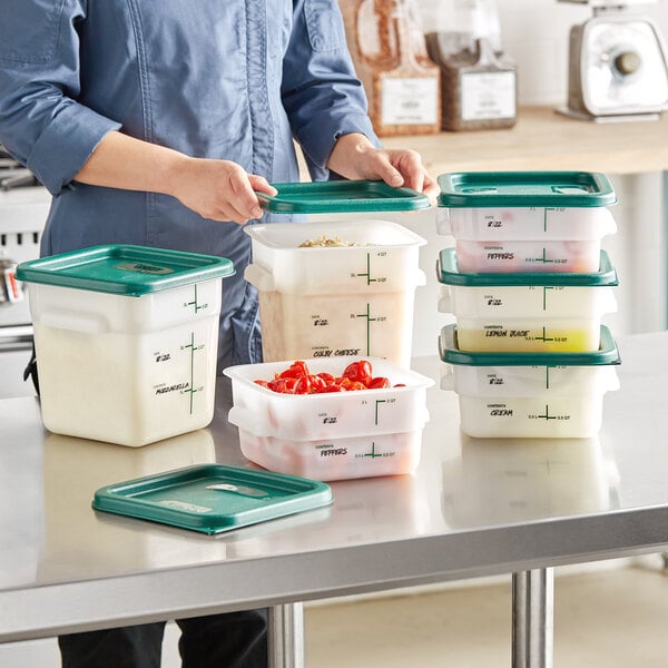 A woman holding a green lid over Vigor square plastic containers on a kitchen counter.