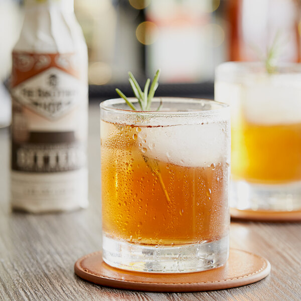 A glass of whiskey with a sprig of rosemary on top.