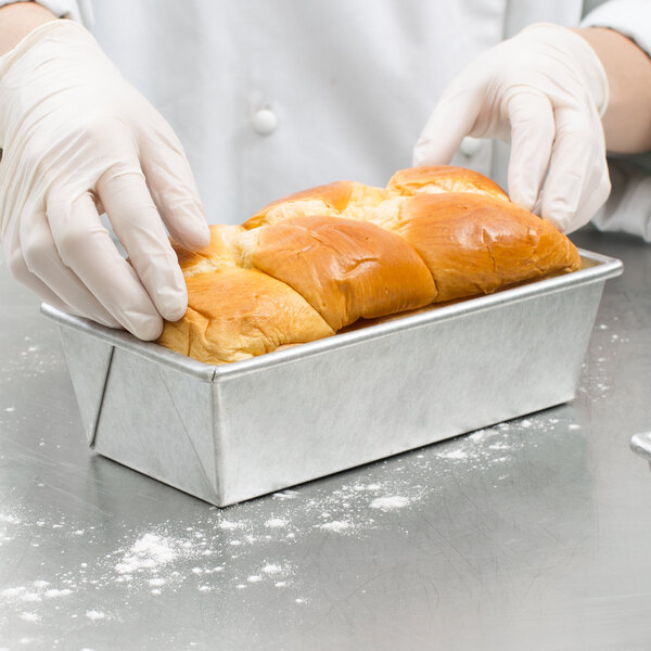A person in gloves holding a loaf of bread baked in a Chicago Metallic bread loaf pan.