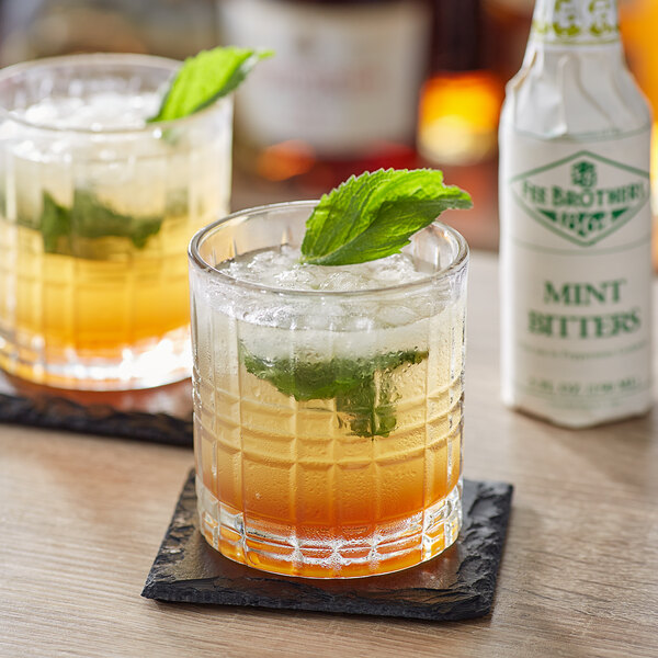 Two glasses of drinks with Fee Brothers Mint Bitters and mint leaves on top.
