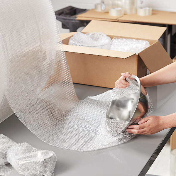 A woman wrapping a silver bowl with Pregis bubble wrap.