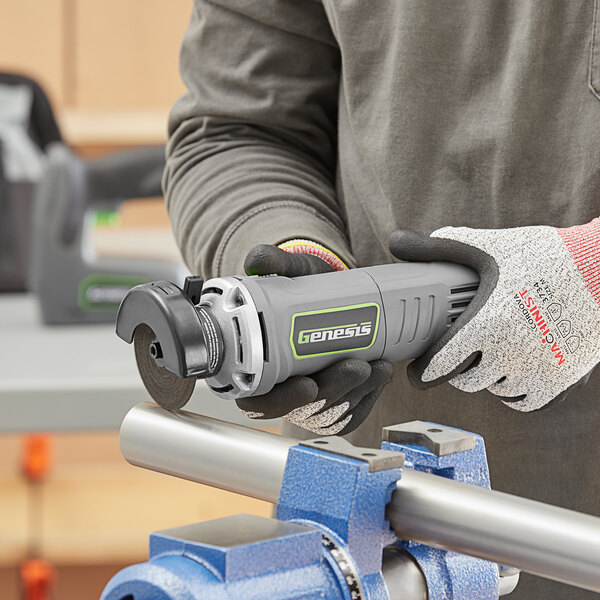 A person uses a Genesis 3" cut-off tool to cut a piece of wood.