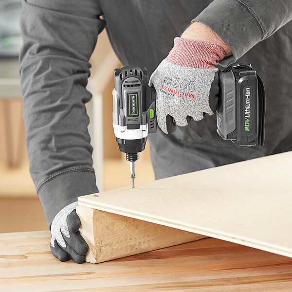 A person using a Genesis cordless impact driver to drill a piece of wood.