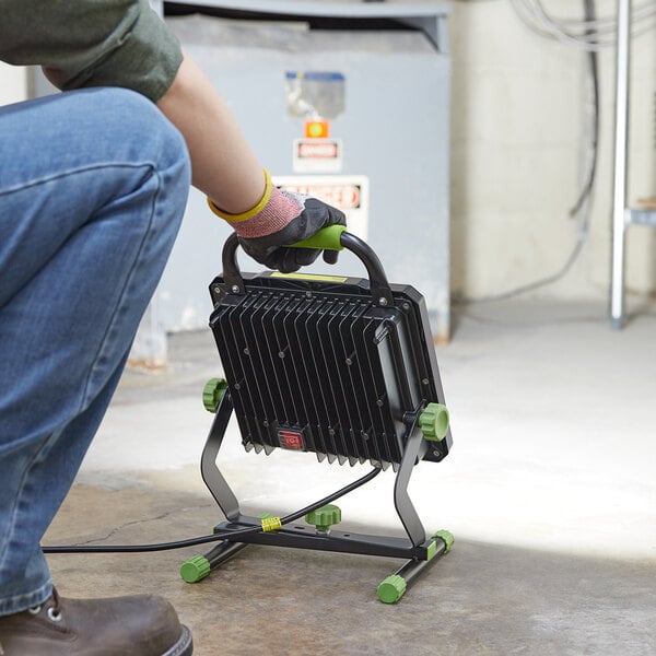 A person using a black and green PowerSmith LED work light.