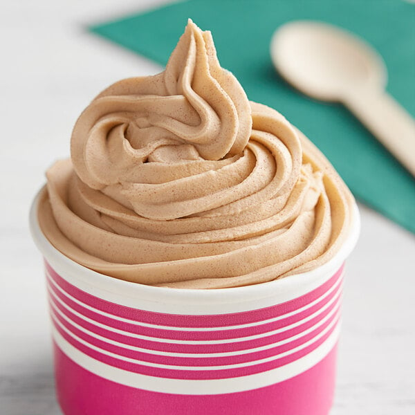 A cup of cookie butter soft serve with a spoon.