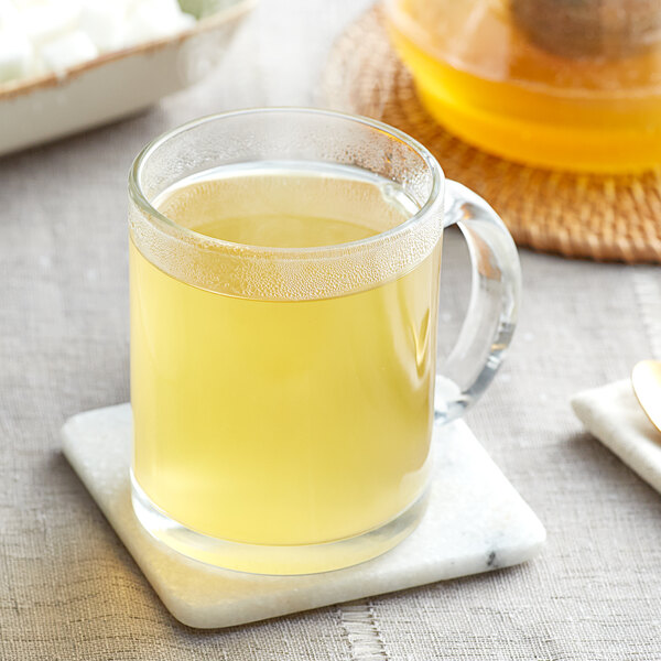 A glass mug of Davidson's Organic Digest Herbal tea with liquid on a coaster.