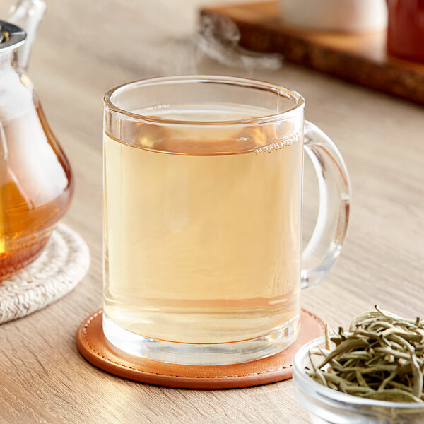 A glass mug of Davidson's Organic Silver Needles loose leaf tea next to a bowl of loose leaf tea.