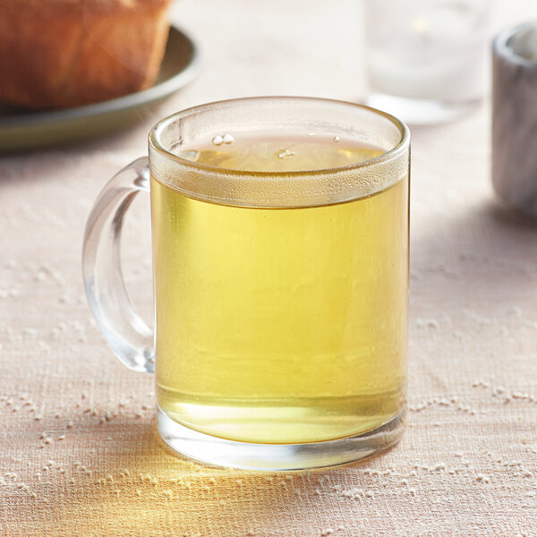 A glass mug of Davidson's Organic Genmaicha tea with a yellow liquid.