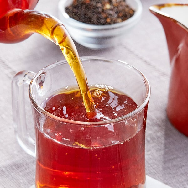 A glass cup of Davidson's Organic Orange Spice loose leaf tea being poured.