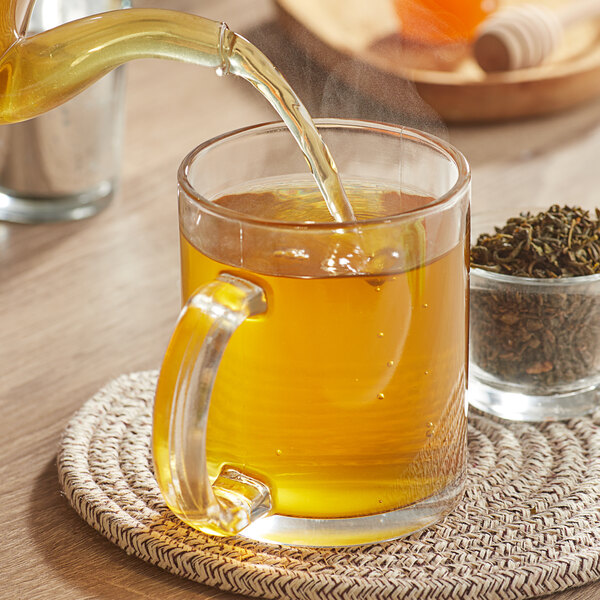 A glass mug of yellow Davidson's Organic Jasmine Almond with Orange tea.