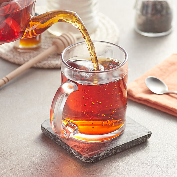 Loose leaf tea being poured into a glass cup.