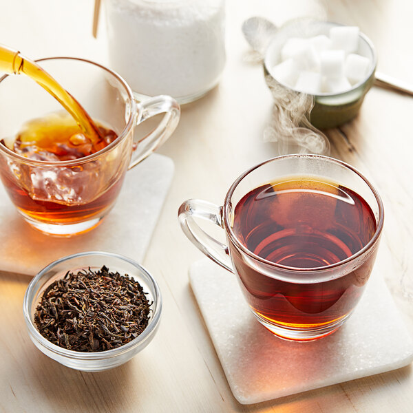 A glass cup of Davidson's Organic Lapsang Souchong Black Tea with brown liquid being poured into it.