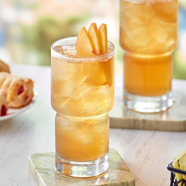A glass of Davidson's Organic Ginger Peach Iced Tea with a slice of apple on top.