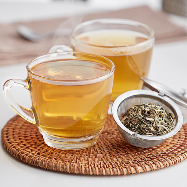 A strainer full of Davidson's Organic Green with Lemon Ginseng tea leaves over a cup of tea.