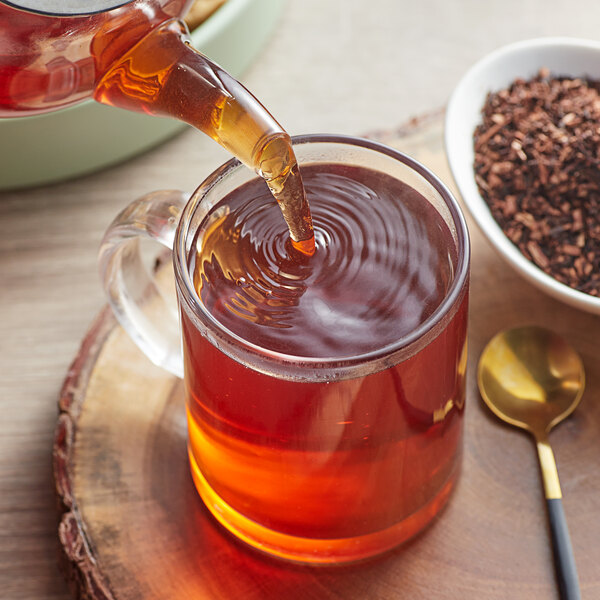 Davidson's Organic South African Honeybush Herbal tea being poured into a glass cup.