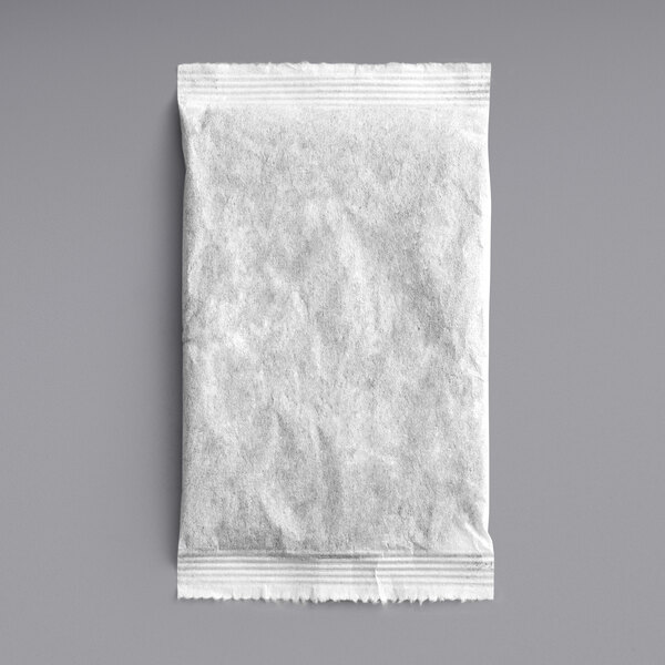 A white paper bag with Davidson's Organic Tropical Iced Tea Filter Packs on a gray surface.