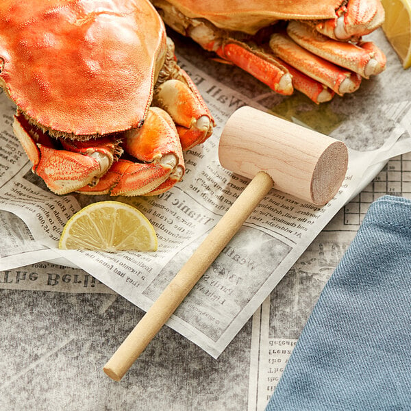A pair of crabs with a Choice Wooden Lobster Mallet and lemon on newspaper.