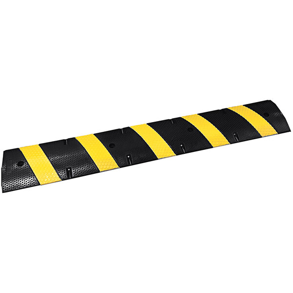 A black and yellow speed bump with yellow reflective stripes and cat eye reflectors.