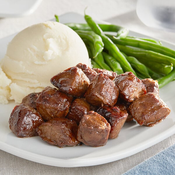 A plate of Gardein Plant-Based Be'f Tips with mashed potatoes and green beans.