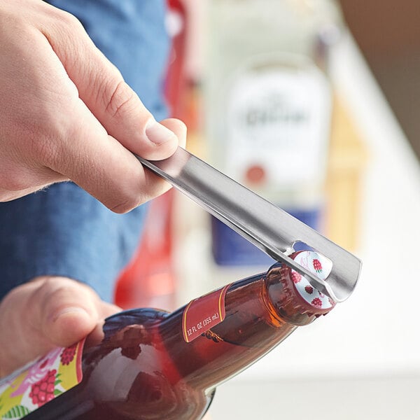 A person using a Choice nickel-plated steel bottle opener to open a bottle of beer.