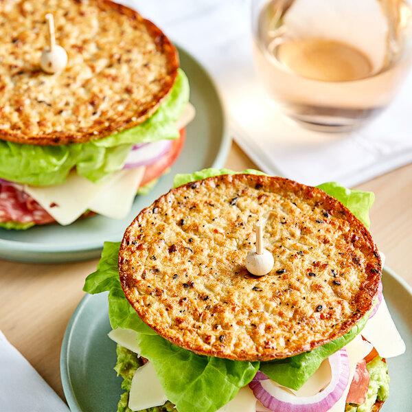 Two cheeseburgers on Outer Aisle Everything-Seasoned Cauliflower Sandwich Thins on plates.